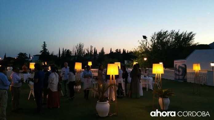 Asistentes al III Aniversario de Sinergia Córdoba en un jardín iluminado al anochecer